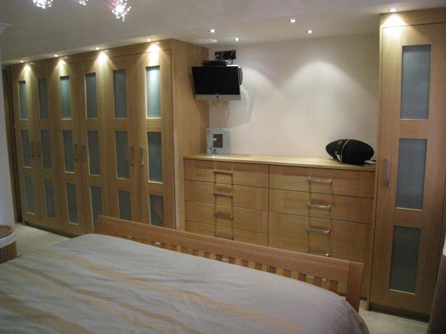 Fitted oak wardrobes and drawers in a bedroom