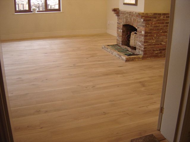 Refurbished room with oak flooring and an exposed brick fireplace