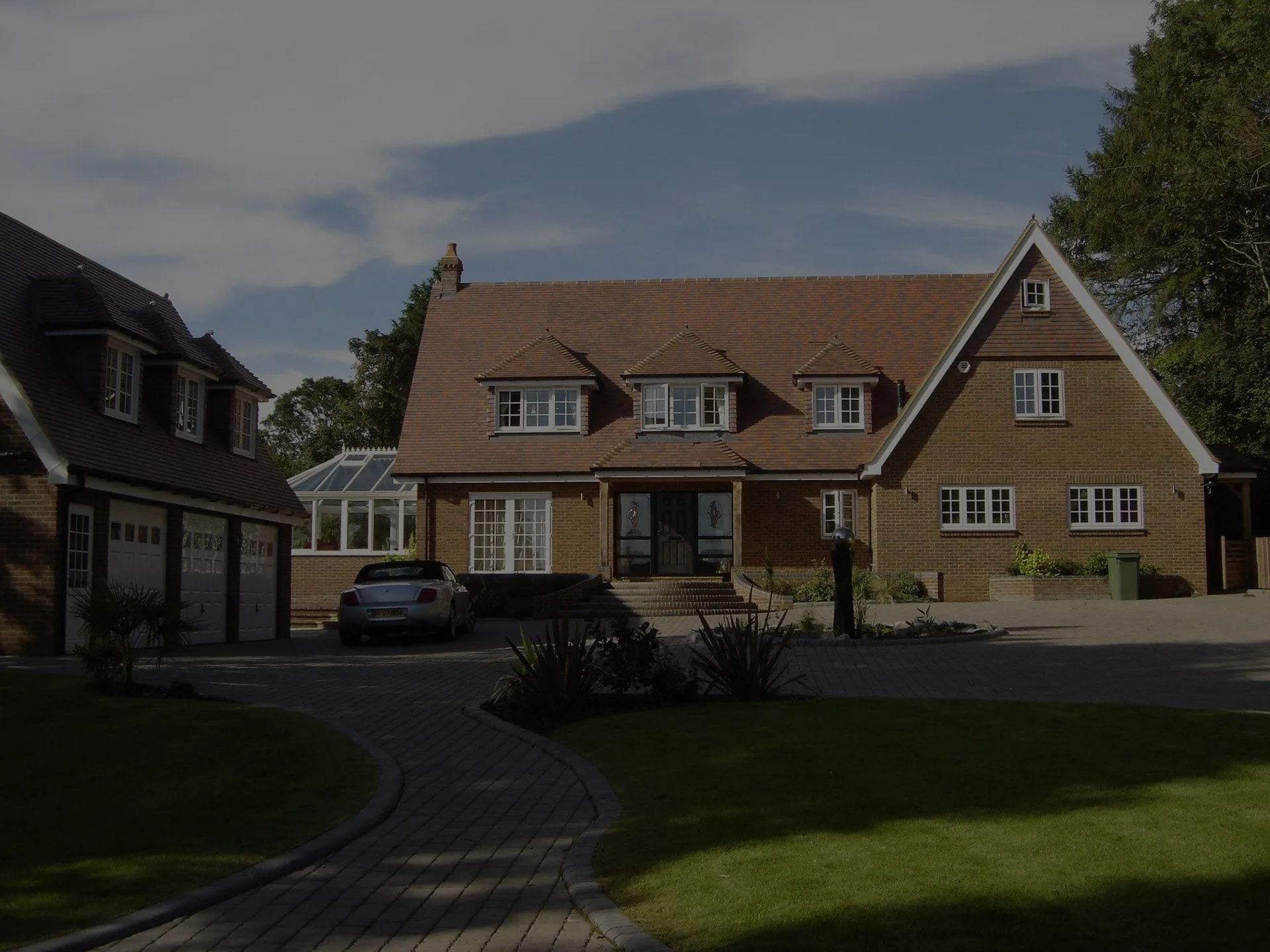 Large brick and tile-hung detached house with a curved brick-paved drive