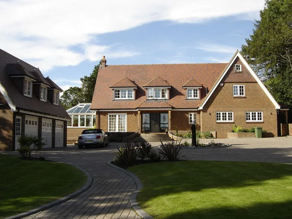 Large detached house with a tiled roof and brick-paved drive