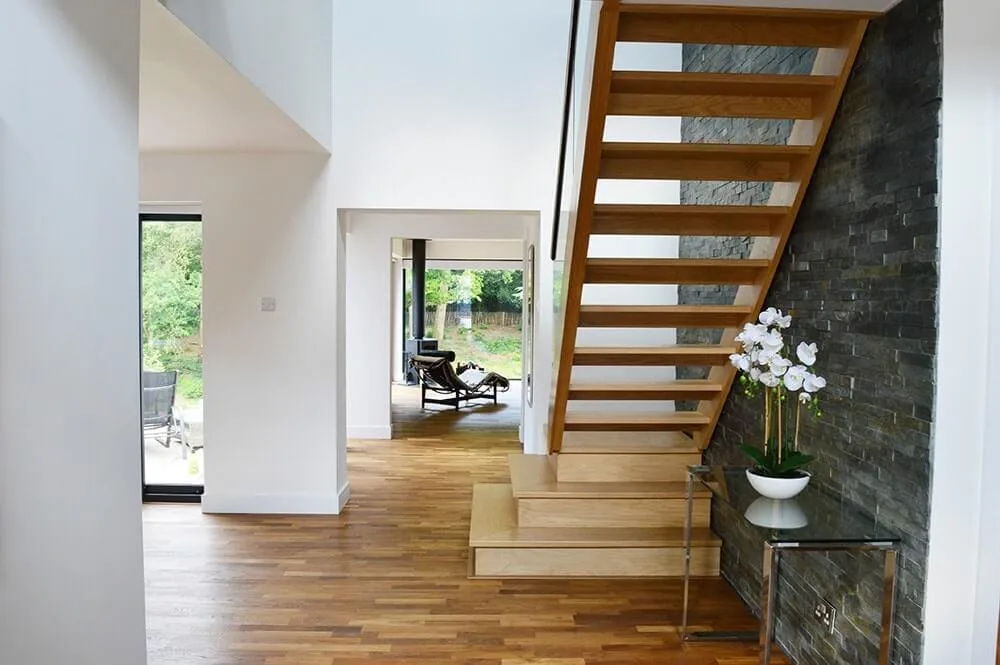 Refurbished hallway with an open-tread staircase and slate wall