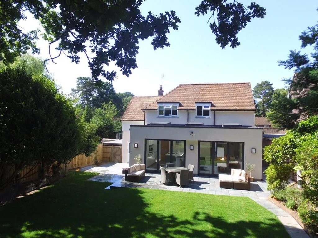 Rear of an extended house with a paved terrace and lawn