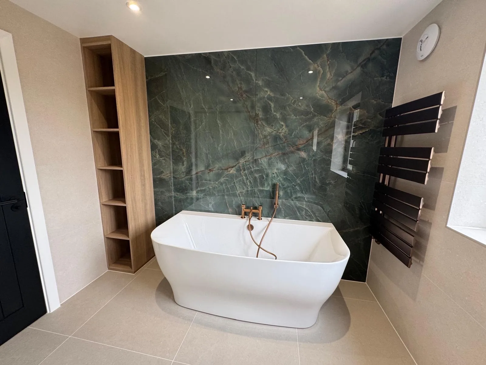Bathroom with a freestanding bath and marble-effect feature wall