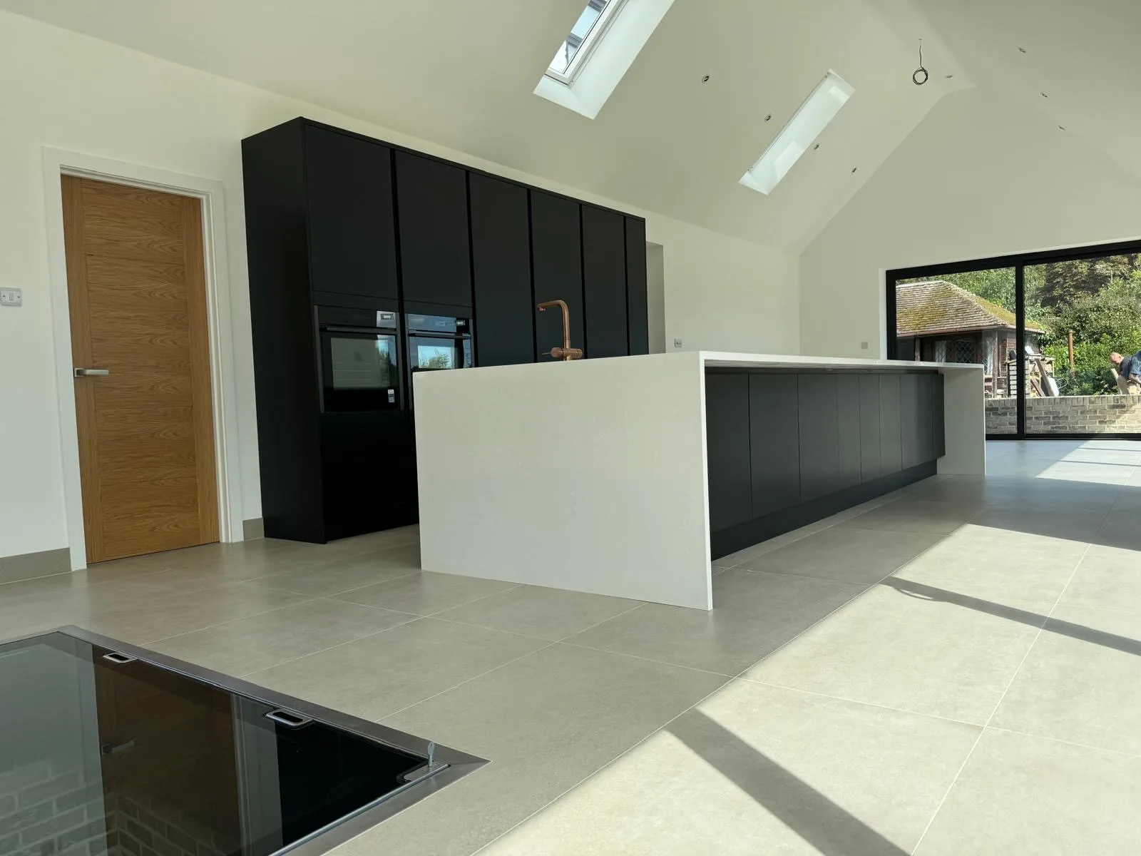 Modern kitchen with a white island and black tall units