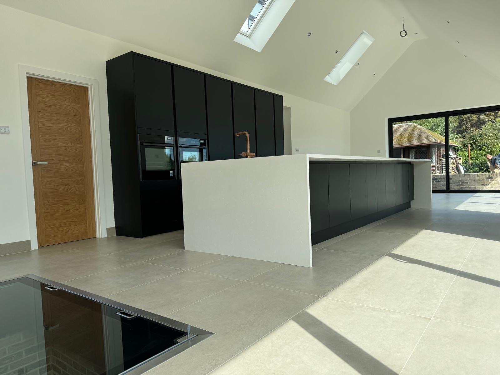 Modern open-plan kitchen refurbishment featuring a marble kitchen island and bespoke navy cabinetry.